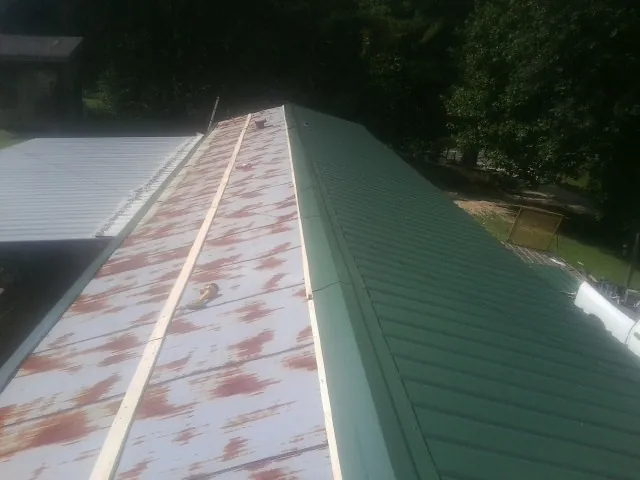 Old rusted panels beside newly installed green metal roofing — Wind Damage Roof Repair by Roofing Brothers in Dunstable