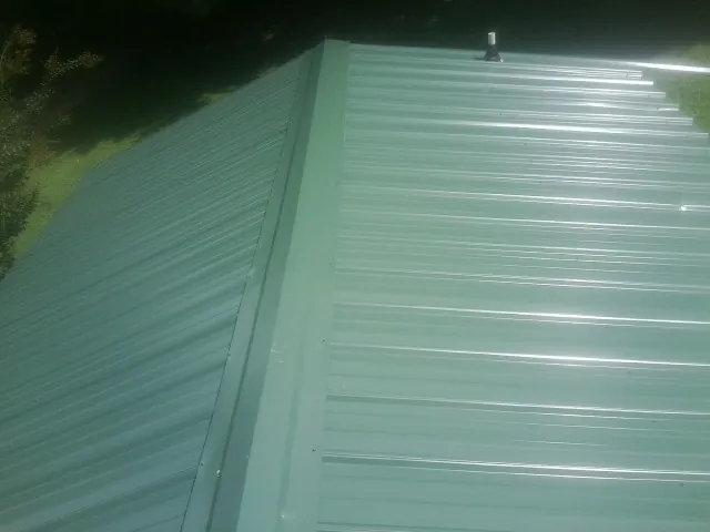 New green metal panels meeting at the ridge of a roof — Flat Roof Repair work by our crew in Dunstable