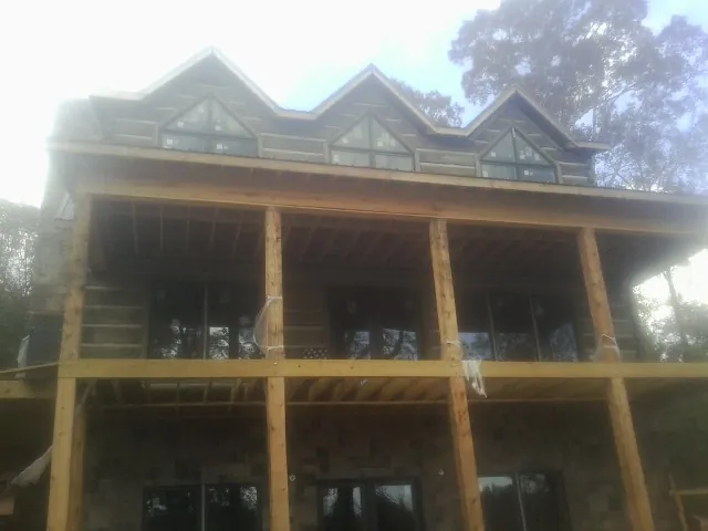 Dormers and porch framing on a large log home under construction — Roof Coating work by our crew in Dunstable