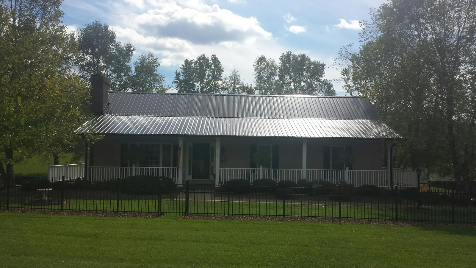 Gray metal roof on a brick ranch with a full width front porch — Gutter Guard Installation work by our crew in Dunstable