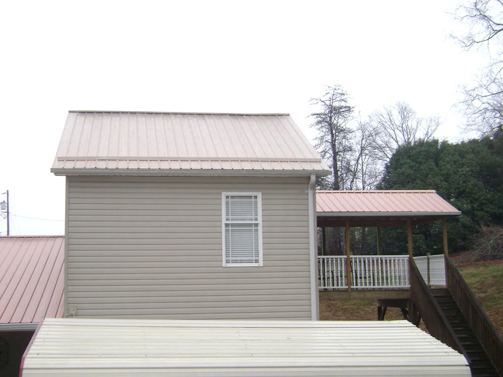 Tan metal roofs on a two story addition and attached porch, from a Roof Replacement job in Dunstable