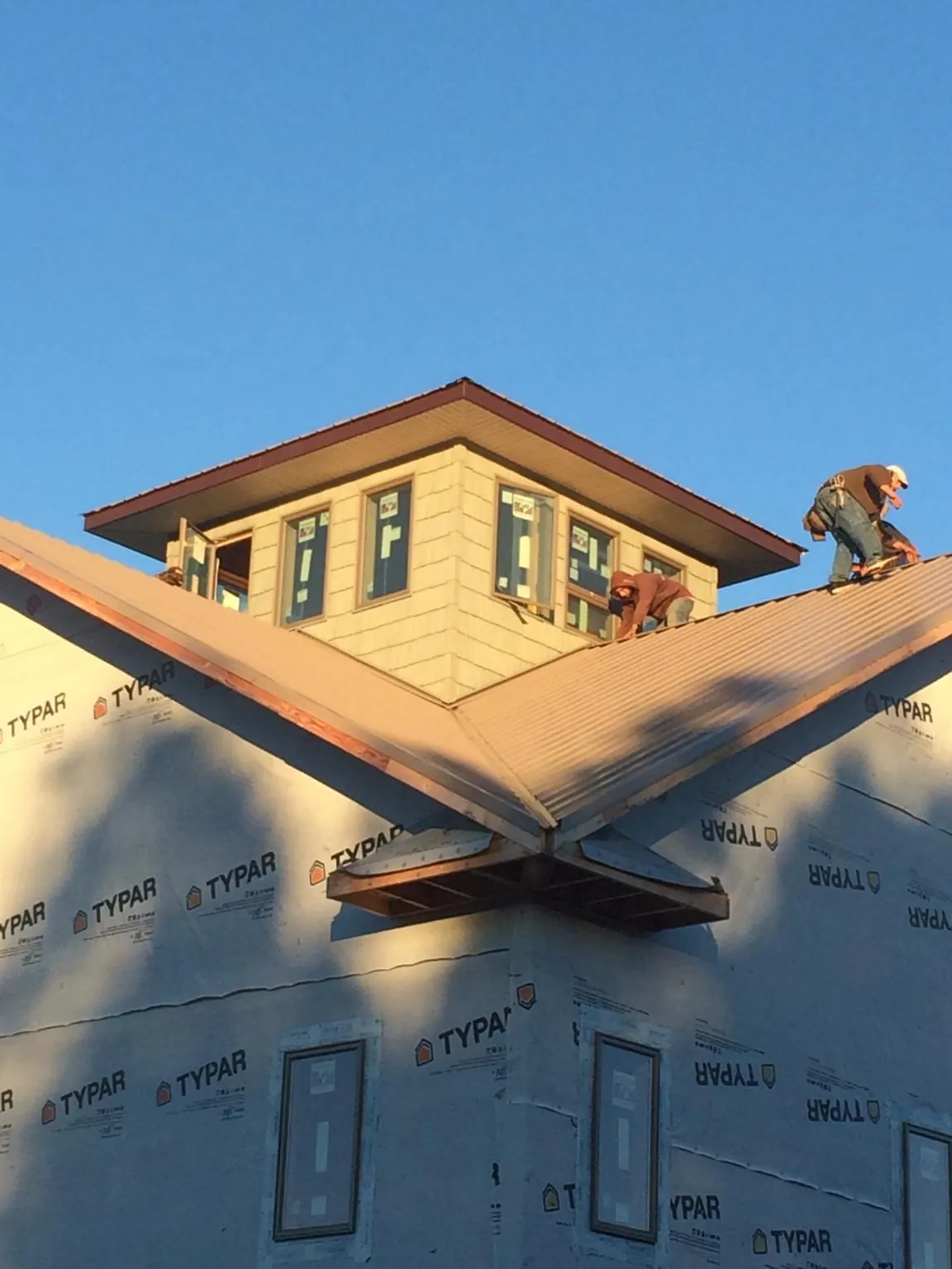 Roofers working around a rooftop cupola on a new metal roof at sunset — Roof Waterproofing in Dunstable by Roofing Brothers